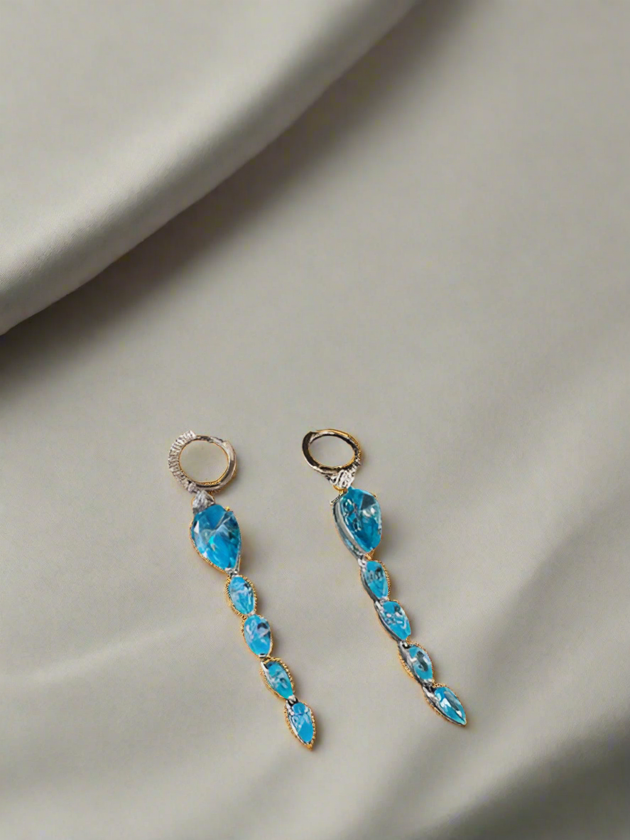 Blue gemstone earrings on a gray fabric background