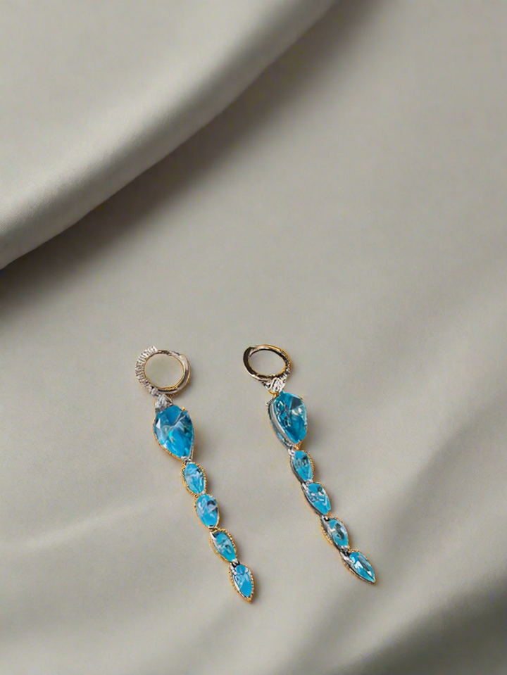 Blue gemstone earrings on a gray fabric background