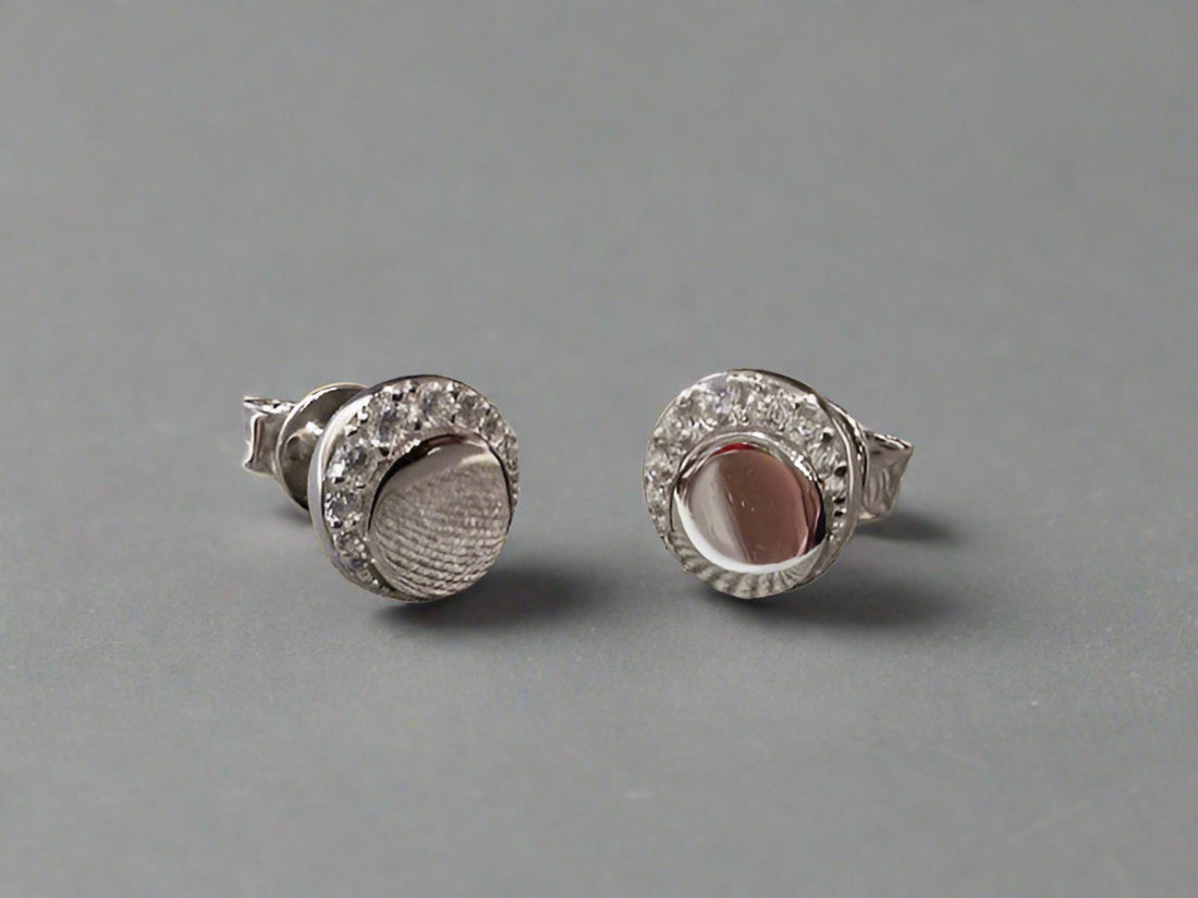 Pair of silver earrings with gemstones on a textured fabric background