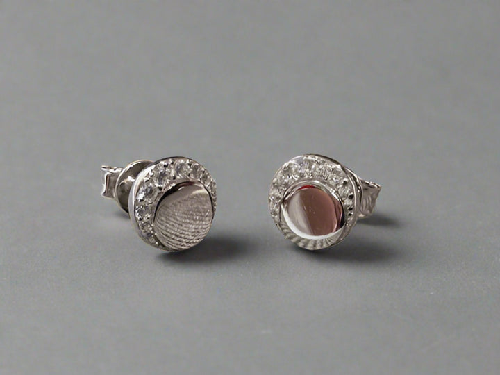Pair of silver earrings with gemstones on a textured fabric background