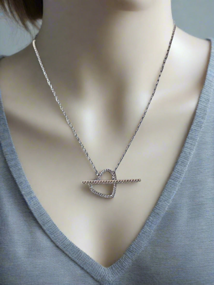 Necklace with a heart-shaped pendant on a mannequin wearing a gray sweater.