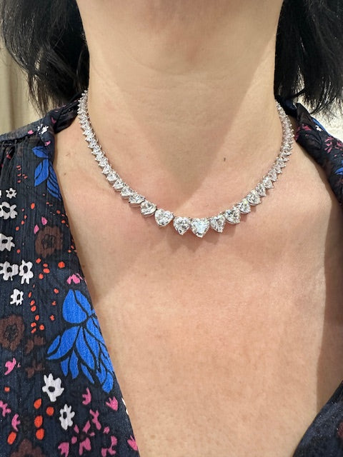 Close-up of a crystal necklace on a person wearing a floral dress.