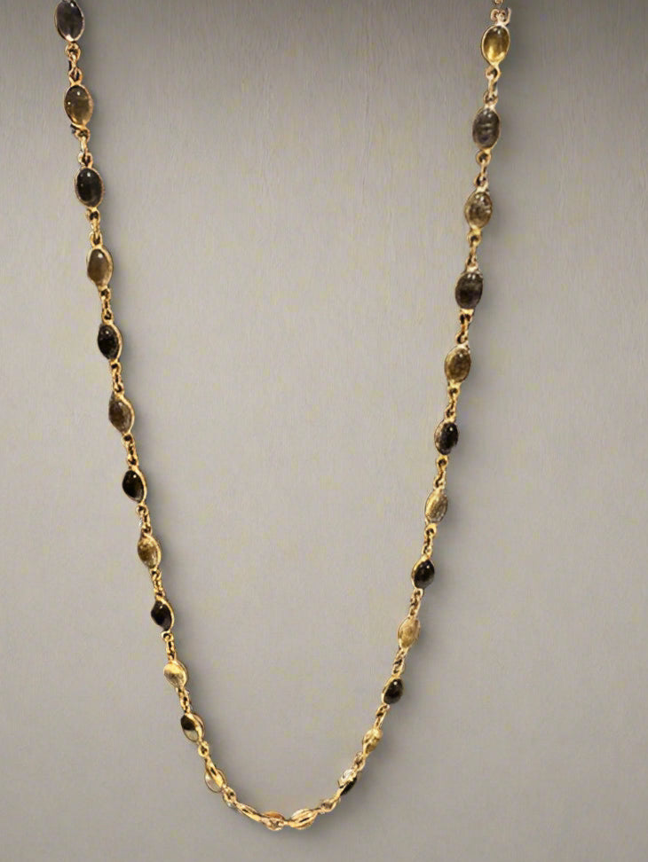 Gold and black beaded necklace on a gray background