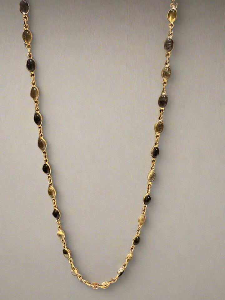Gold and black beaded necklace on a gray background