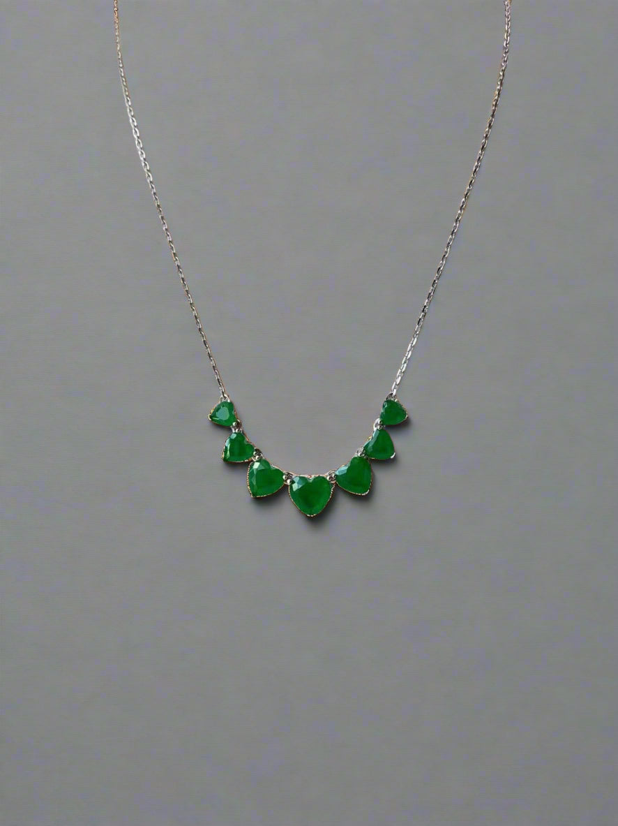 Necklace with heart-shaped stones on plain backgrund.
