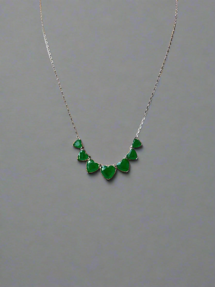 Necklace with heart-shaped stones on plain backgrund.
