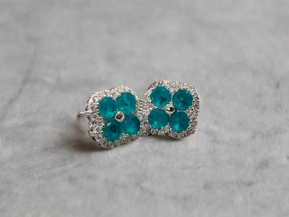 Pair of teal flower-shaped earrings on a textured surface