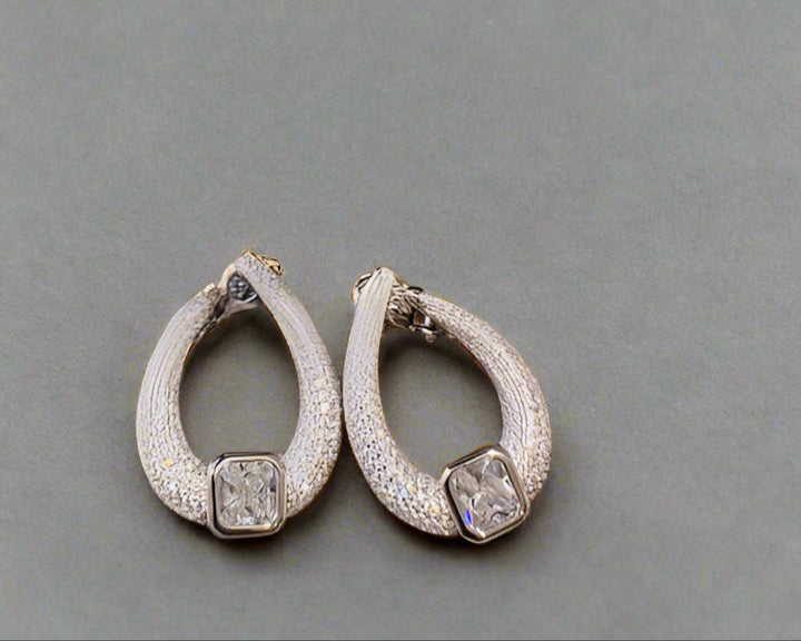 Pair of silver hoop earrings on a textured gray surface